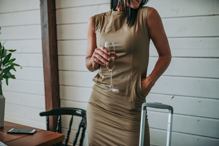 Woman with luggage having wine at home