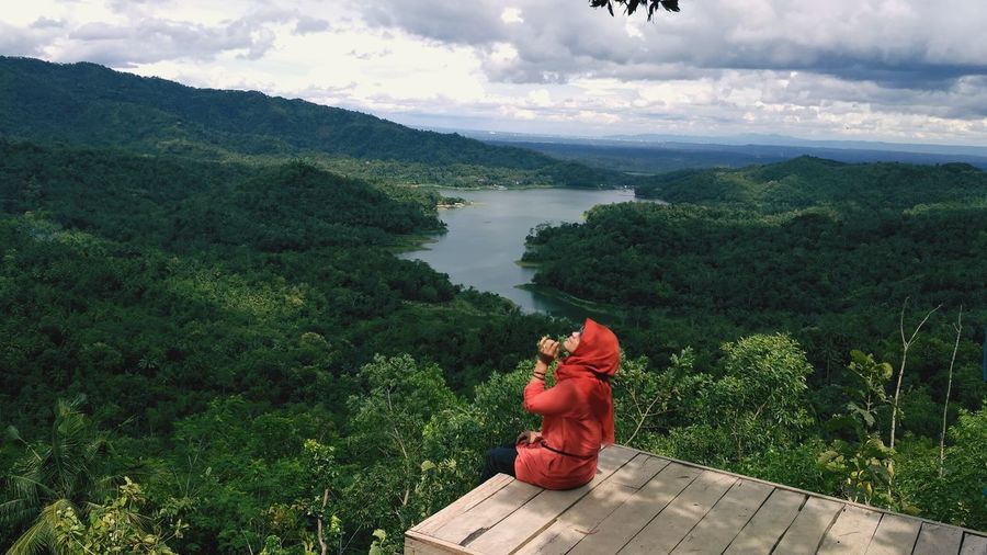 High angle view of woman sitting by pier against forest