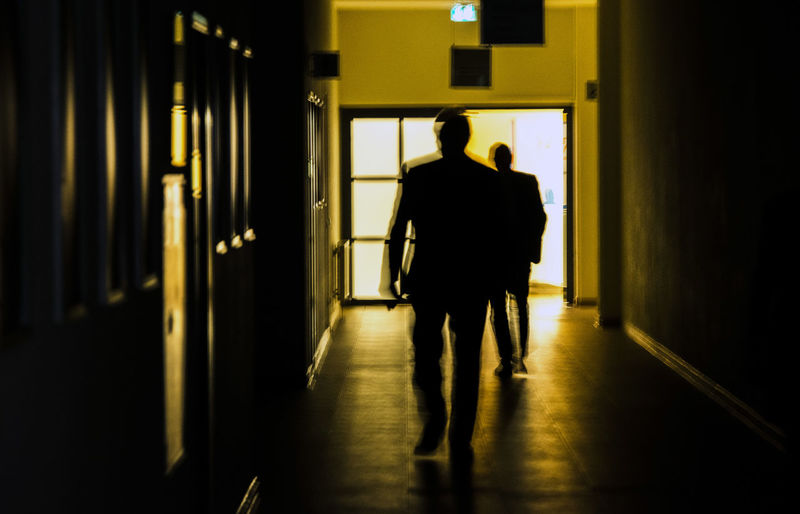 Rear view of silhouette man walking in building