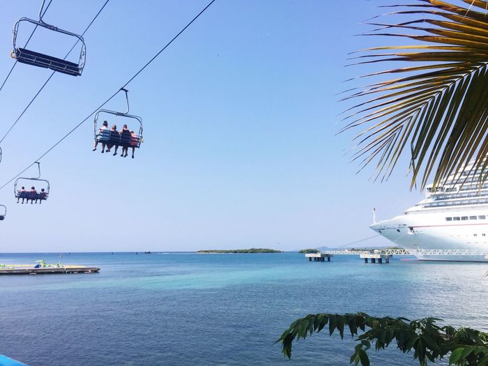 Low angle view of ski lift over sea against clear blue sky