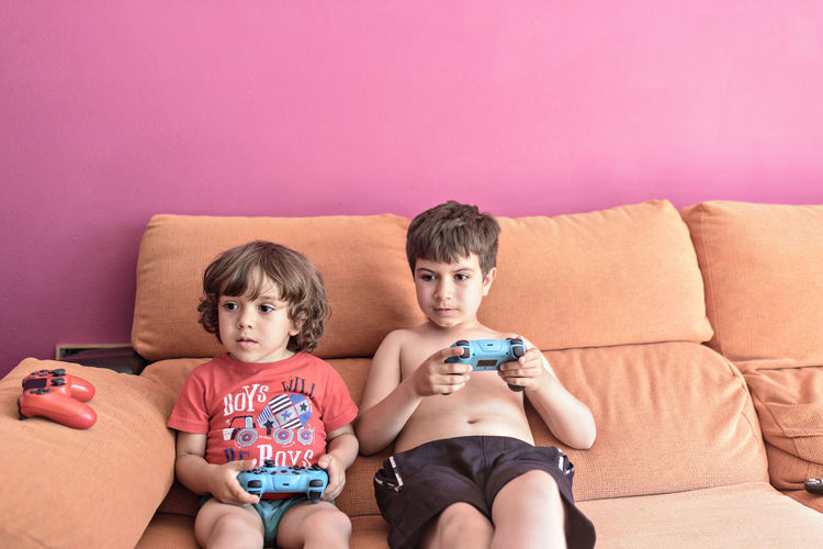 Computer game competition. gaming concept. excited children leaning on the sofa back playing video