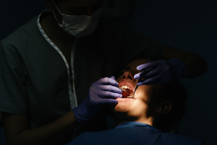 Close-up of dentist examining woman in clinic