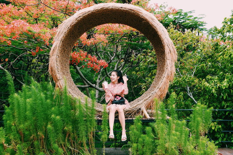 Portrait of smiling young woman sitting by plants