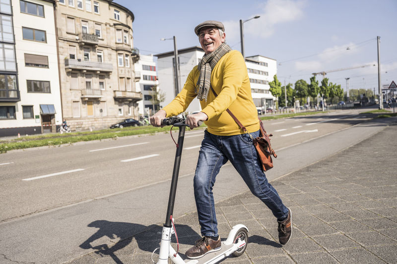 Happy senior man with electric push scooter in the city