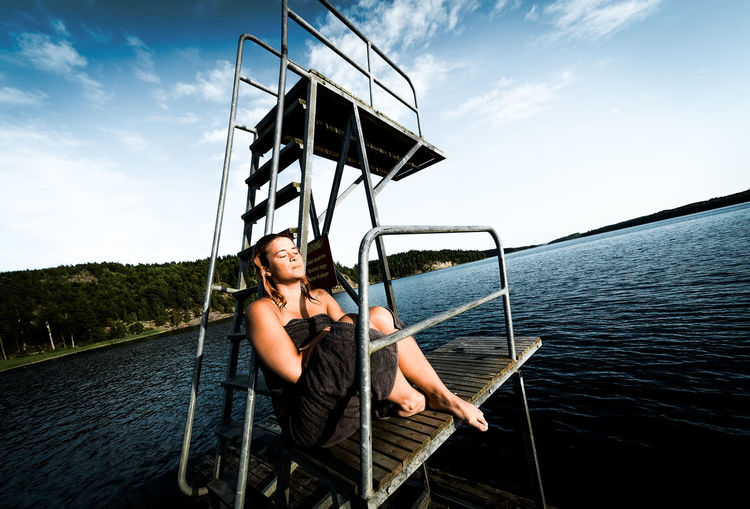 Woman relaxing by diving platform by lake