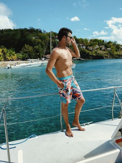 Full length of shirtless man standing on boat
