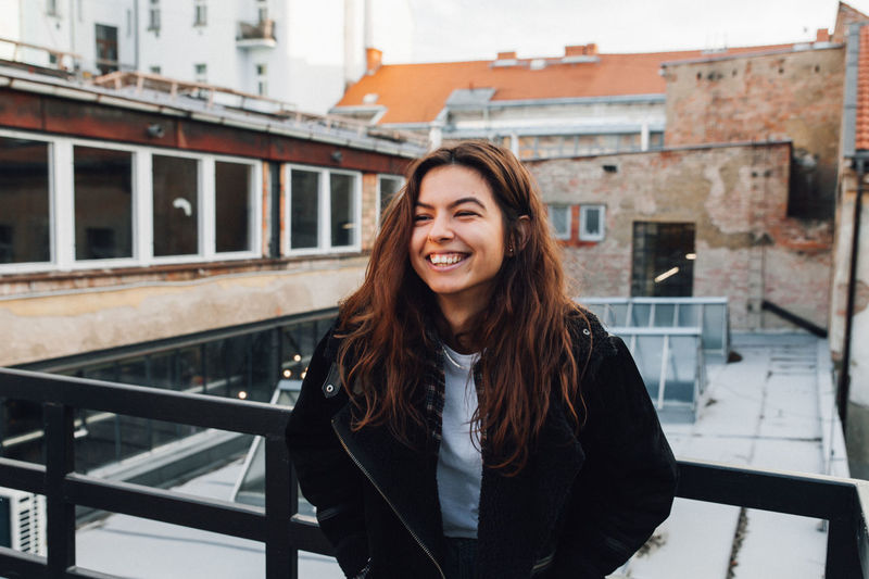 Portrait of smiling woman standing against railing