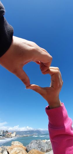 Close-up of hand holding umbrella against clear blue sky