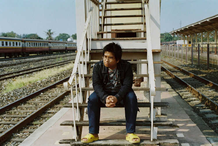 Portrait of young woman sitting on railroad station platform