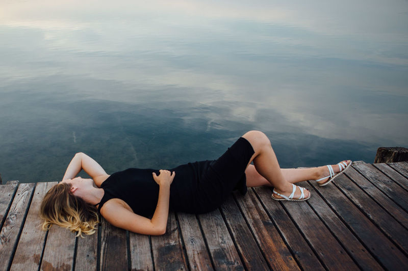 Young woman lying on pier by lake