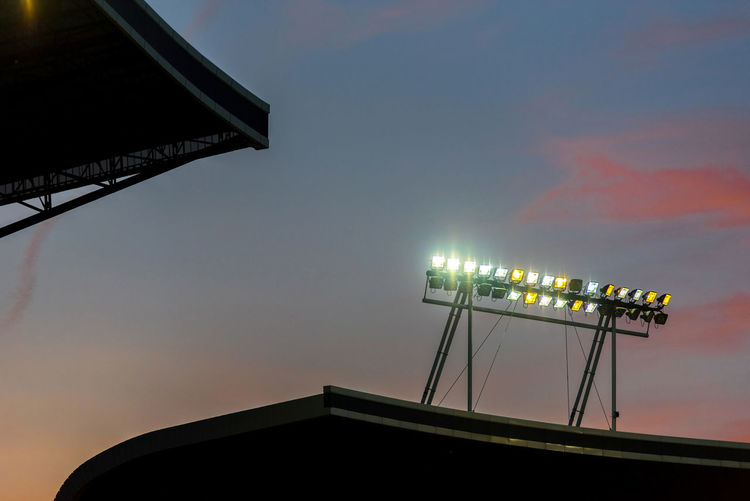 Glowing stadium lights against sunset sky during blue hour