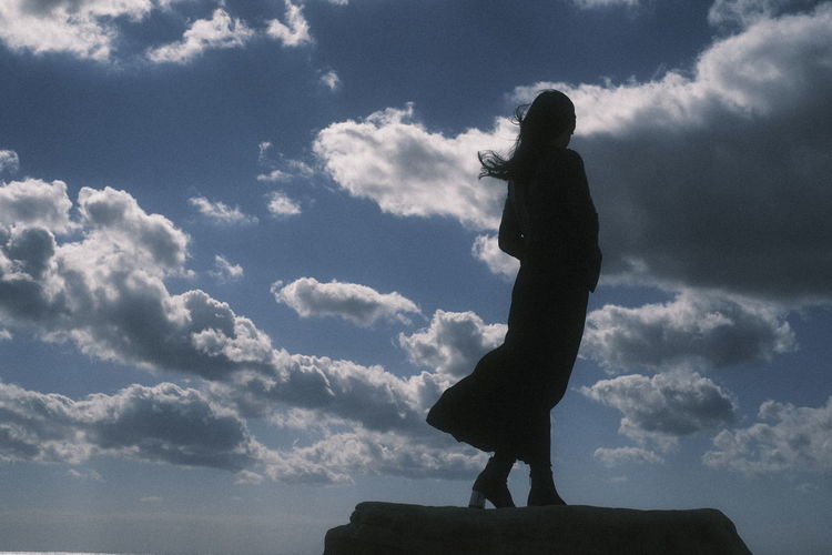Low angle view of silhouette woman standing against sky