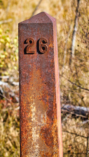 Close-up of rusty sign on field