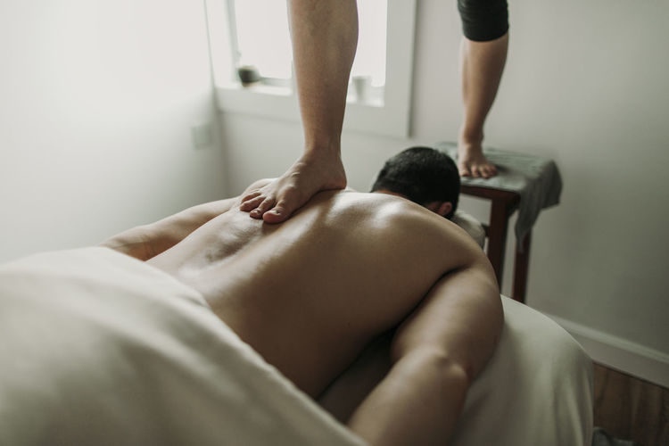 Massage therapist uses her feet to treat male patient's back