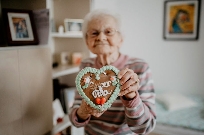 Portrait of senior woman holding gingerbread cookie at home
