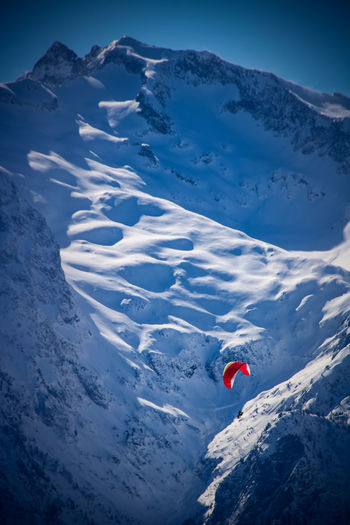 High angle view of person paragliding amidst snowcapped mountain