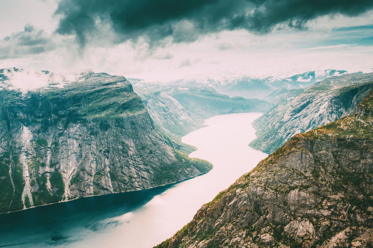 Scenic view of lake amidst snowcapped mountains against cloudy sky