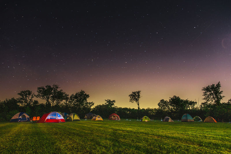 Tents on grassy field against star field at night