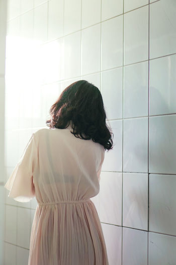 Rear view of woman standing in bathroom at home
