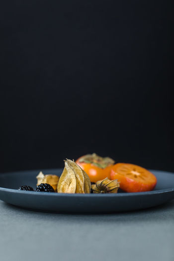 Physalis or cape gooseberries, blackberries and kumquats on a plate as a healthy snack