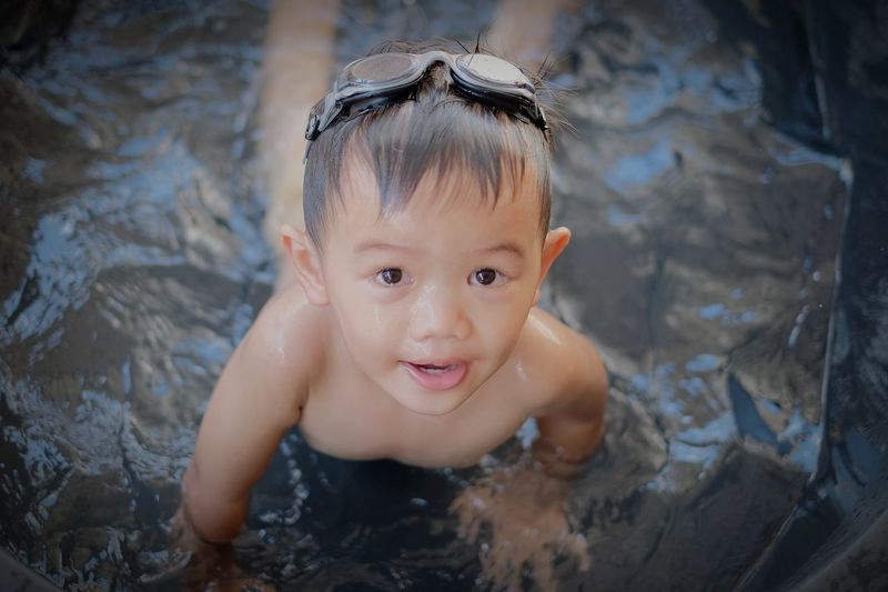 High angle portrait of cute boy smiling in wading pool