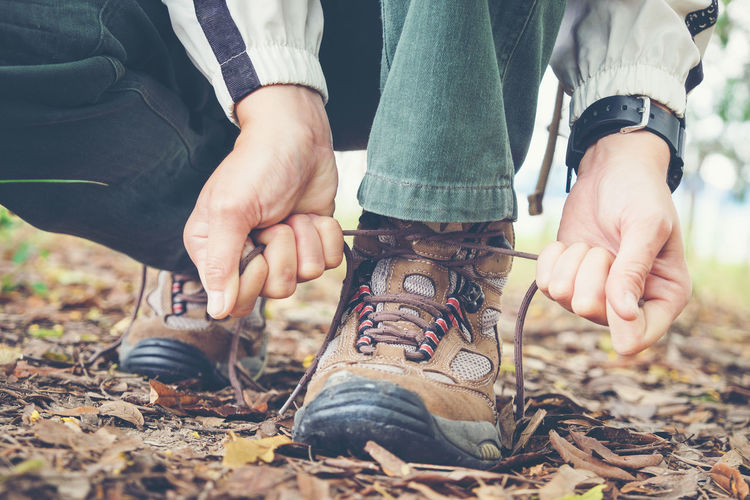 Low section of man tying shoelace on field