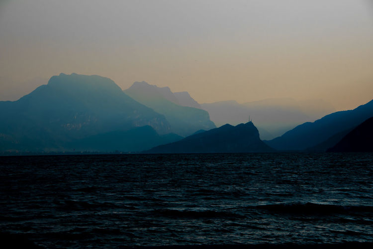 Scenic view of sea and mountains against sky at sunset