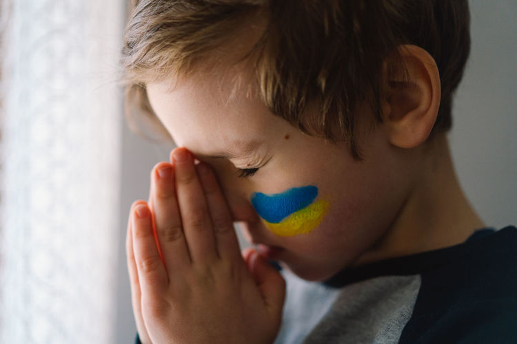 Ukrainian boy closed her eyes and praying to stop the war in ukraine.
