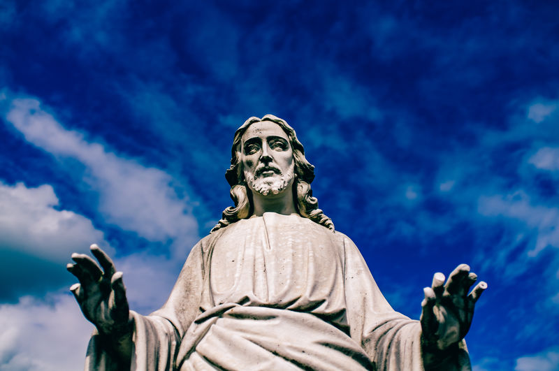 Low angle view of jesus statue against blue sky