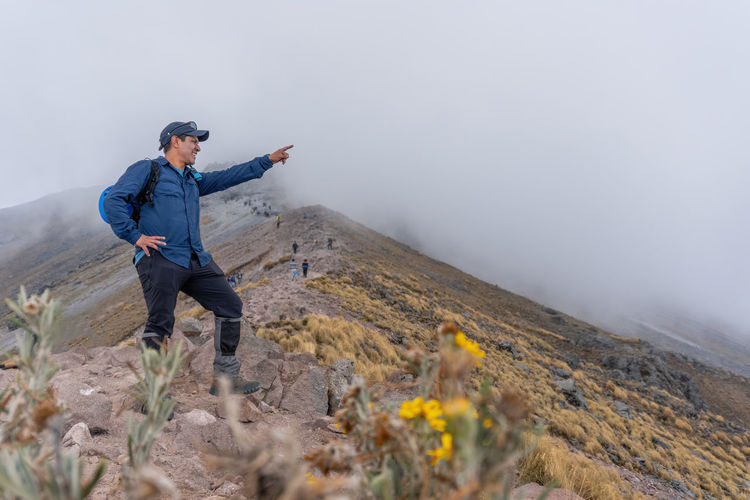 Man pointing while standing on mountain