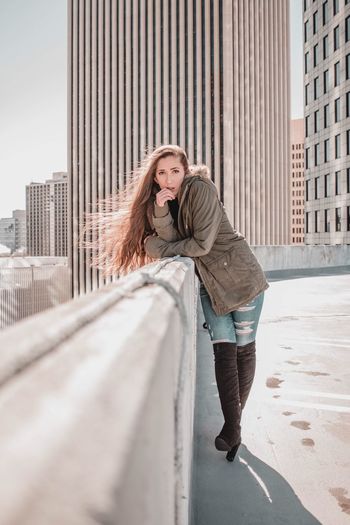 Portrait of smiling young woman standing against buildings in city