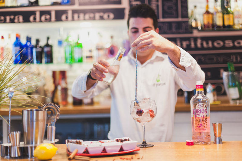 Young bartender preparing drink at counter