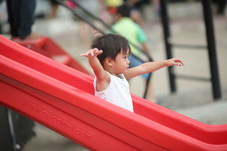 Cute boy looking away on slide in playground