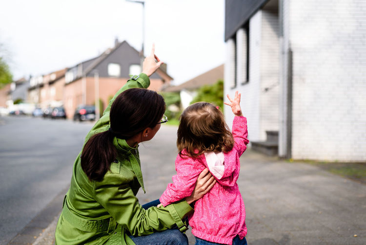 Side view of mother showing direction to daughter on street