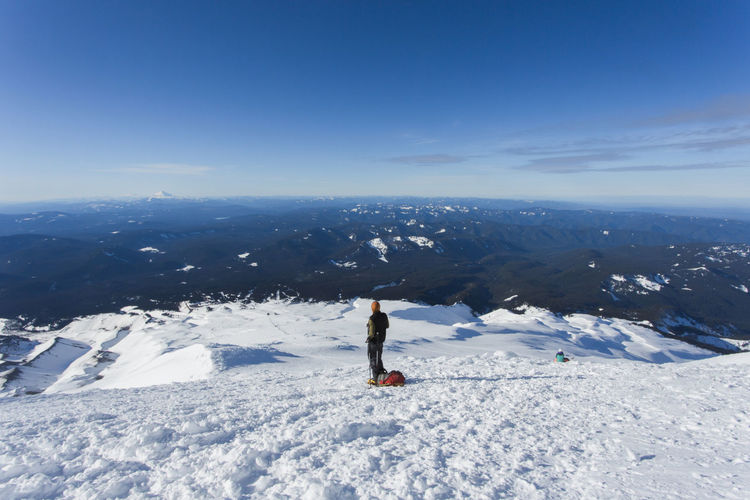 Woman walking on snowcapped mountain against sky during winter