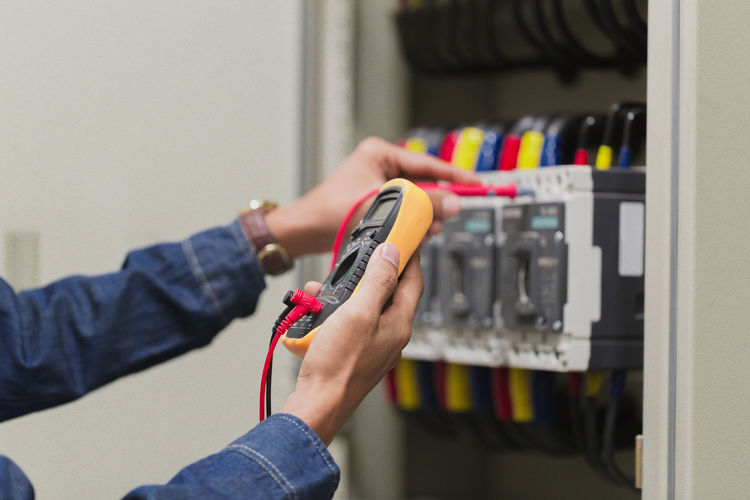 Midsection of man checking electrical equipment