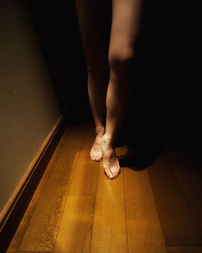 Low section of person standing on hardwood floor