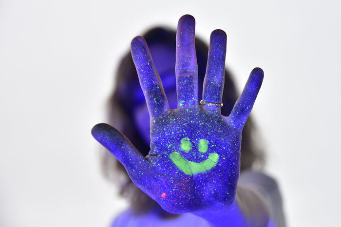 Close-up of woman hand covered with powder paint against purple background