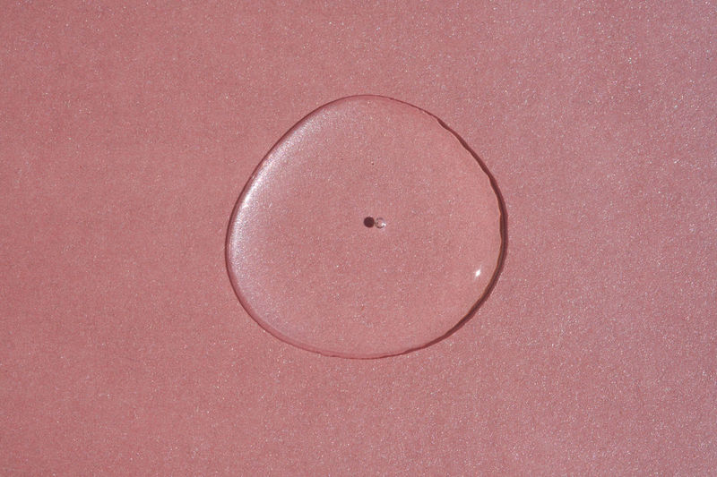A drop of cosmetics or perfume on a pink background.