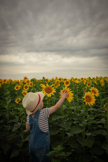 Low angle view of girl standing on field against cloudy sky