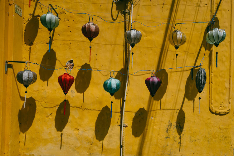 Low angle view of lanterns hanging against yellow wall