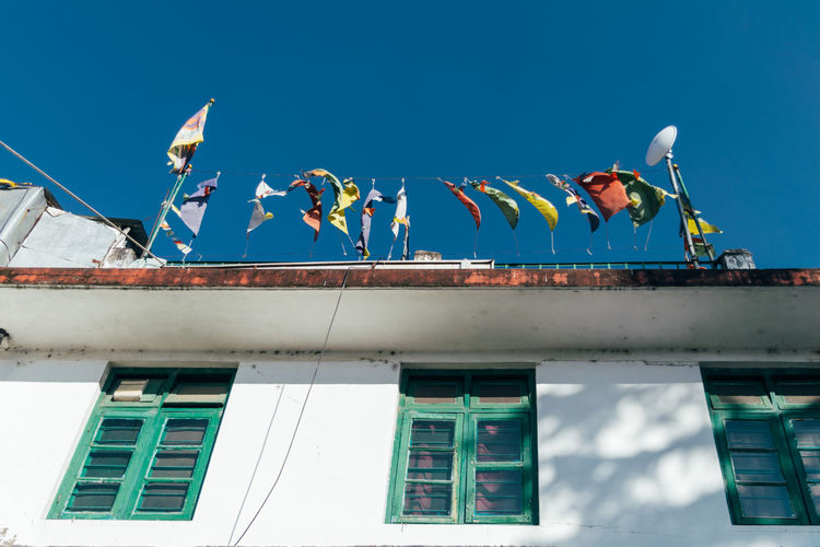 Low angle view of flags on building against blue sky