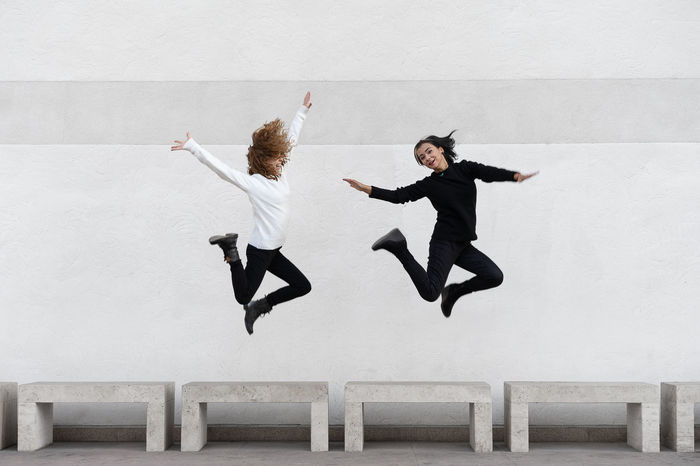 Lesbian couple jumping against wall