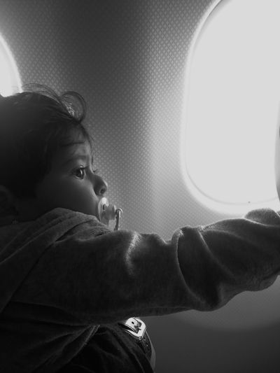 Side view of little girl sucking pacifier in airplane