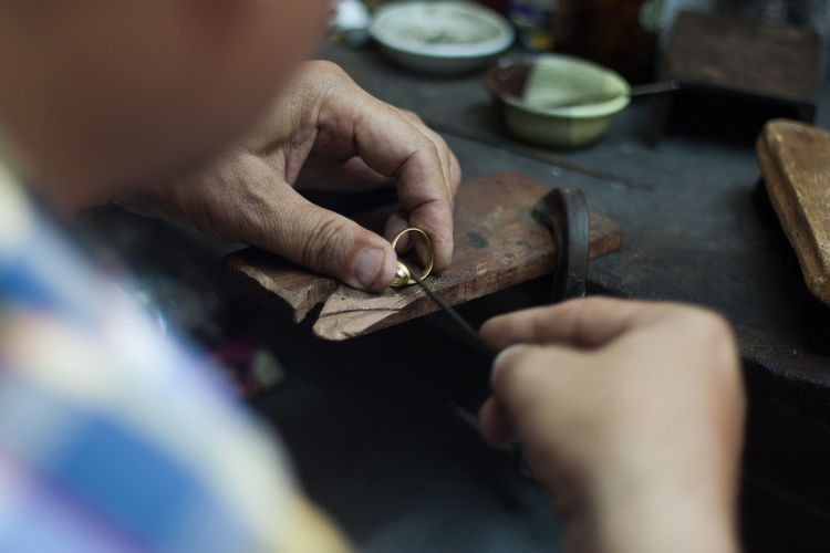 Midsection of man working on jewelry in workshop