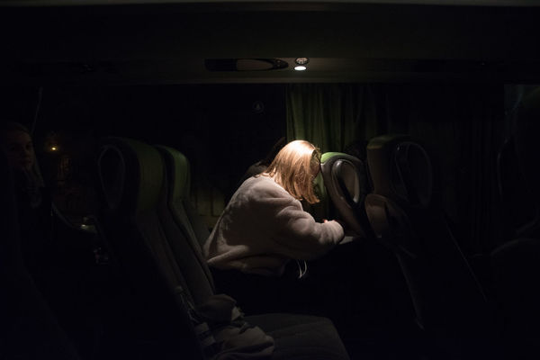 Side view of woman sitting on bus at night