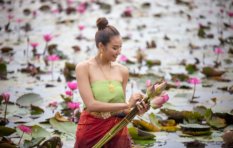 Woman holding pink flower in lake