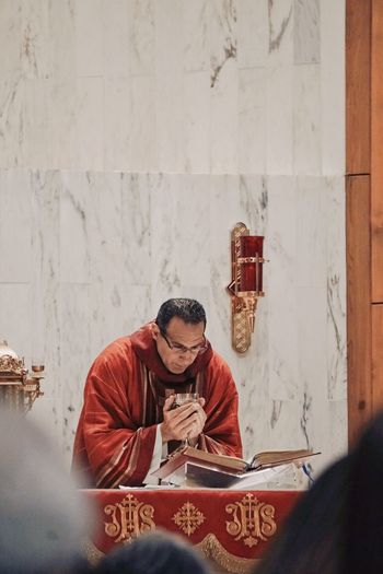 Priest holding chalice while reading book at church