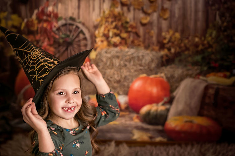 Portrait of cute girl standing by pumpkin