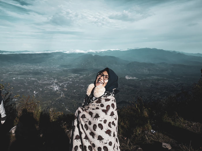 Portrait of woman standing on mountain against sky
